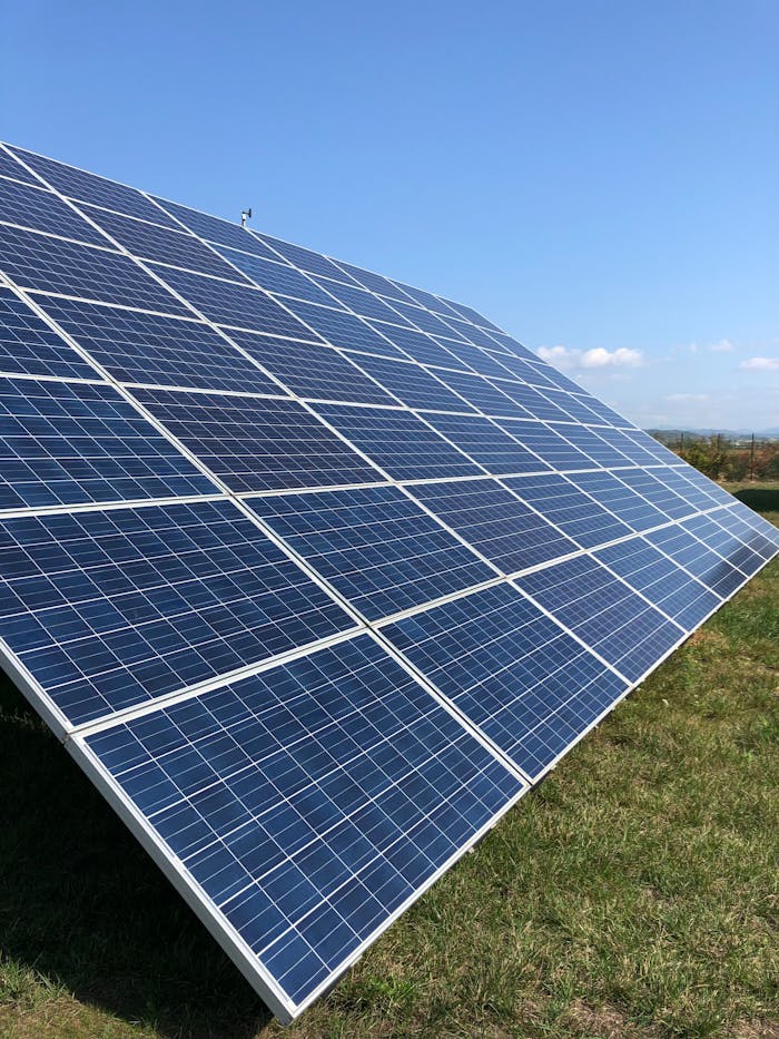 services-img Solar panels in a green field on a sunny day, showcasing renewable energy in Tortona, Italy.